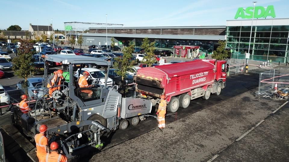 Crummock paver and crew laying asphalt in the car park with a tipper feeding the hopper.
