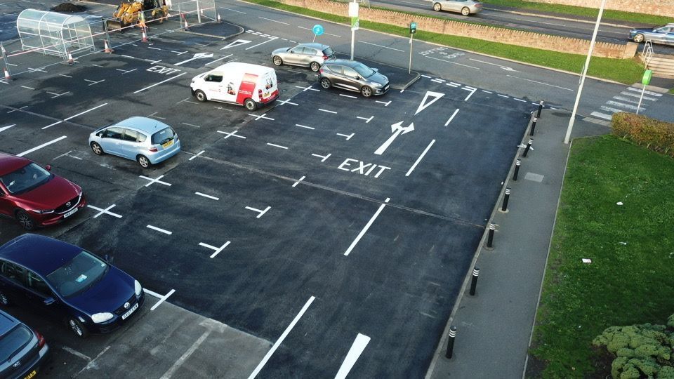 Newly surfaced and marked bays with an exit arrow, cars parked either side.