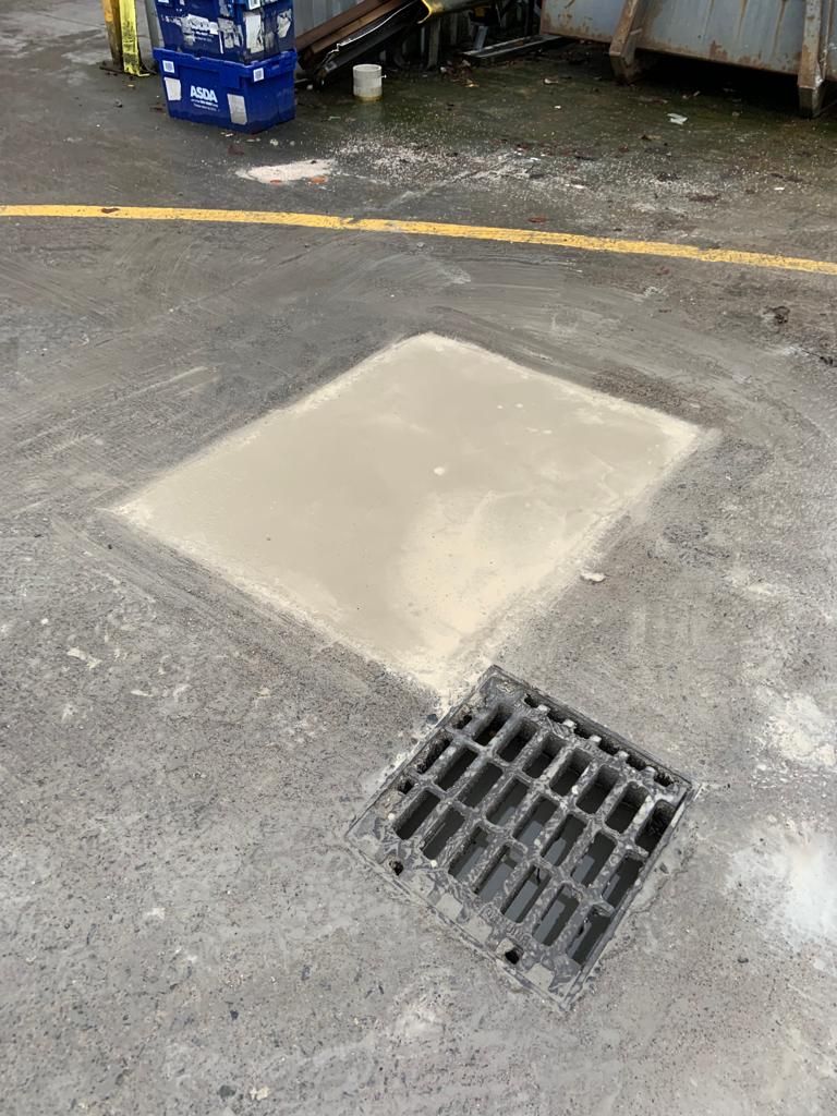 New concrete surround cast around a gully grating in the service yard.