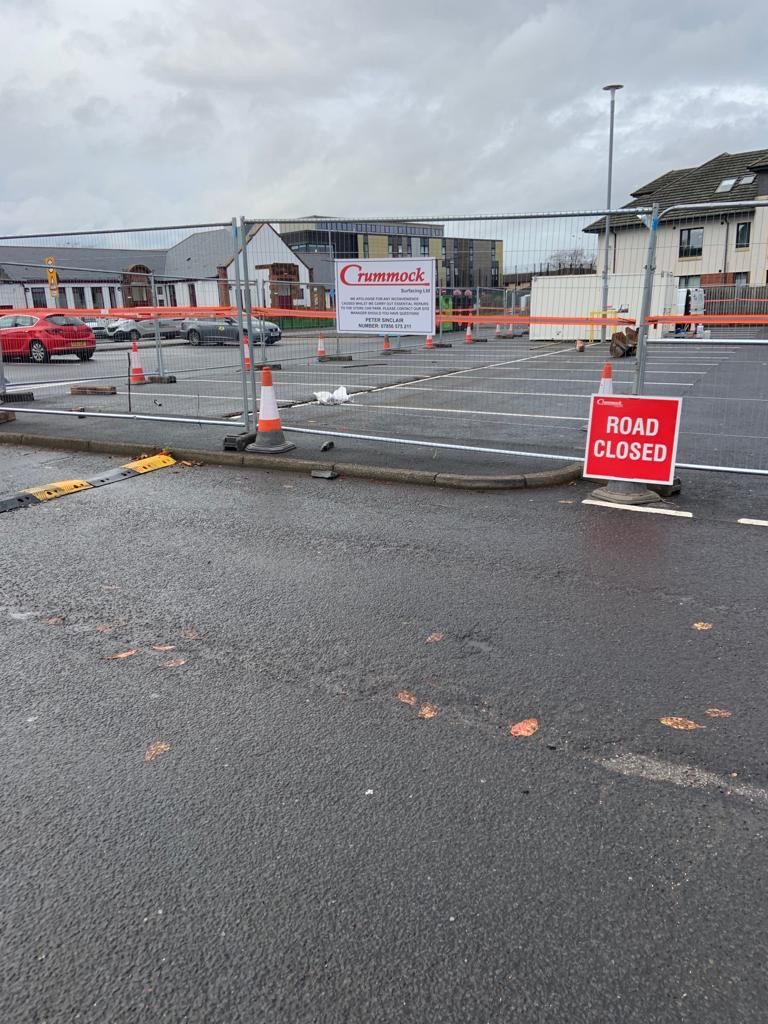 Site hoarding with a Crummock board and a road closed sign across the car park access.