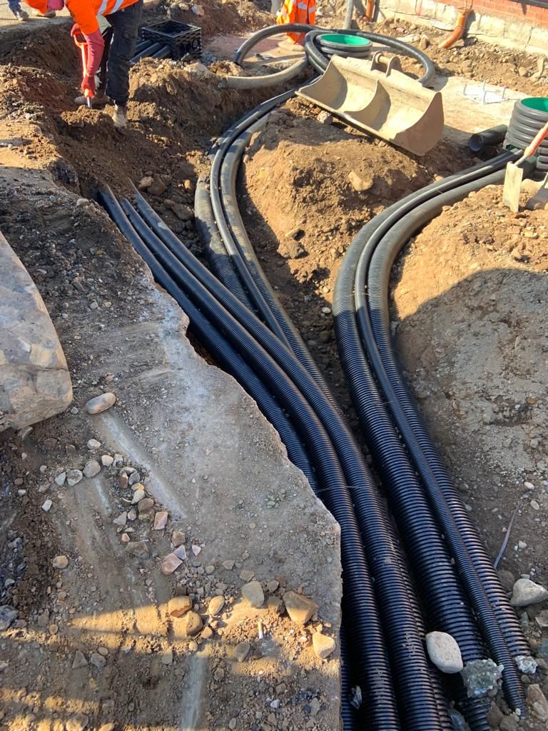 Runs of black ducting curving through the excavation towards the chambers.