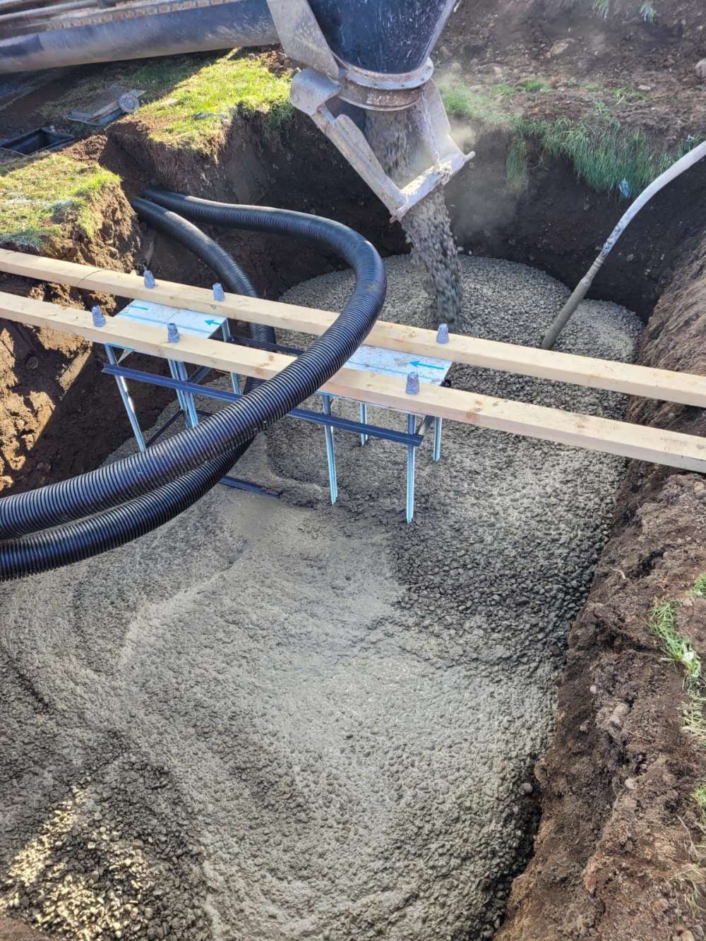 Ducting laid in an open trench on timber supports before backfilling.