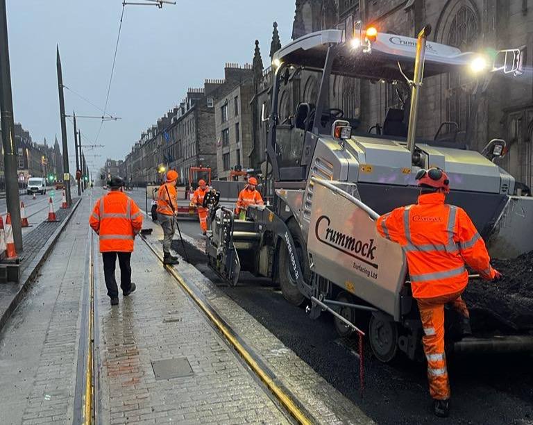 A Crummock paver laying asphalt alongside tram rails on an Edinburgh street.